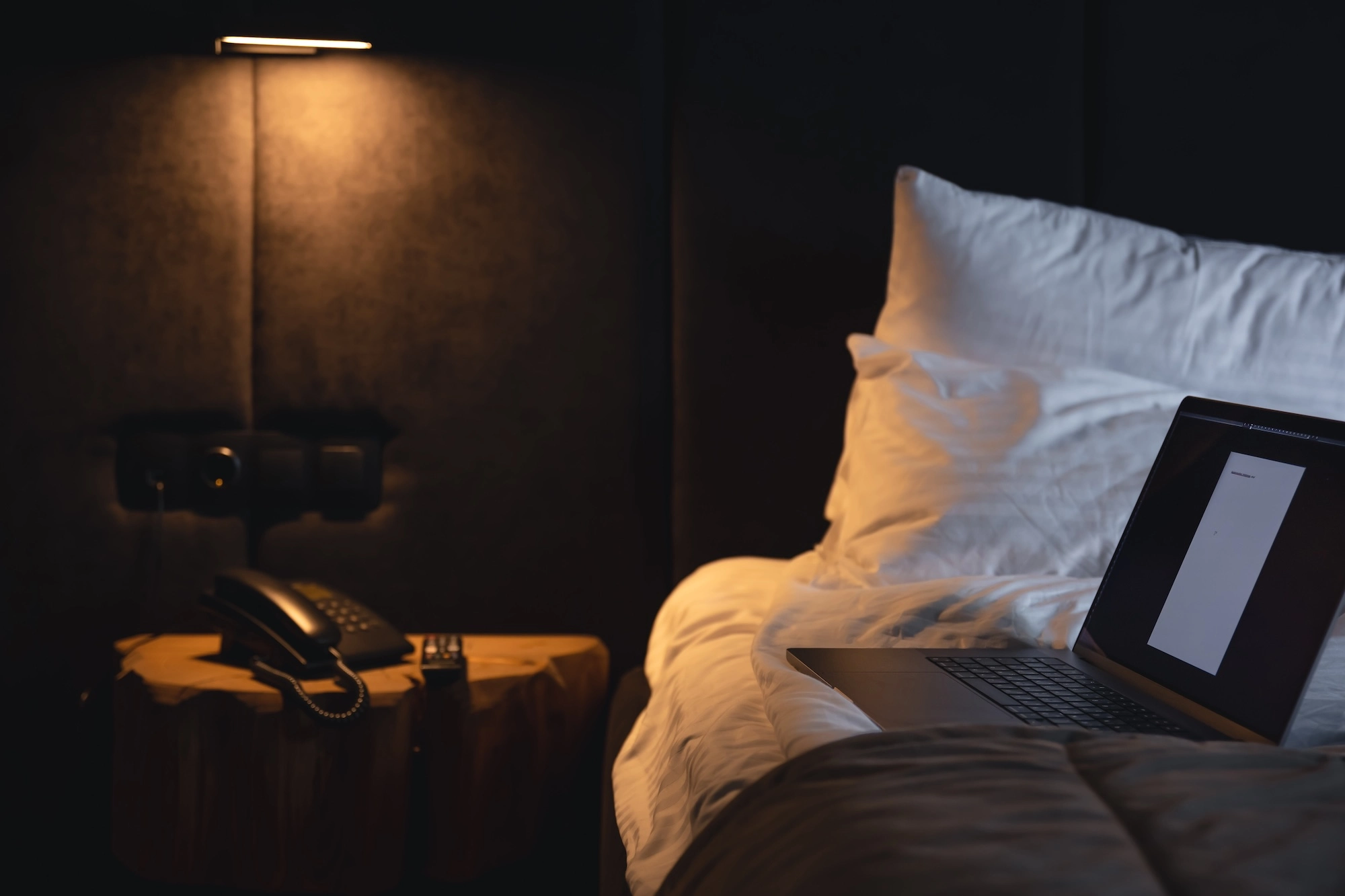 Laptop open on a hotel bed at night, mid-booking